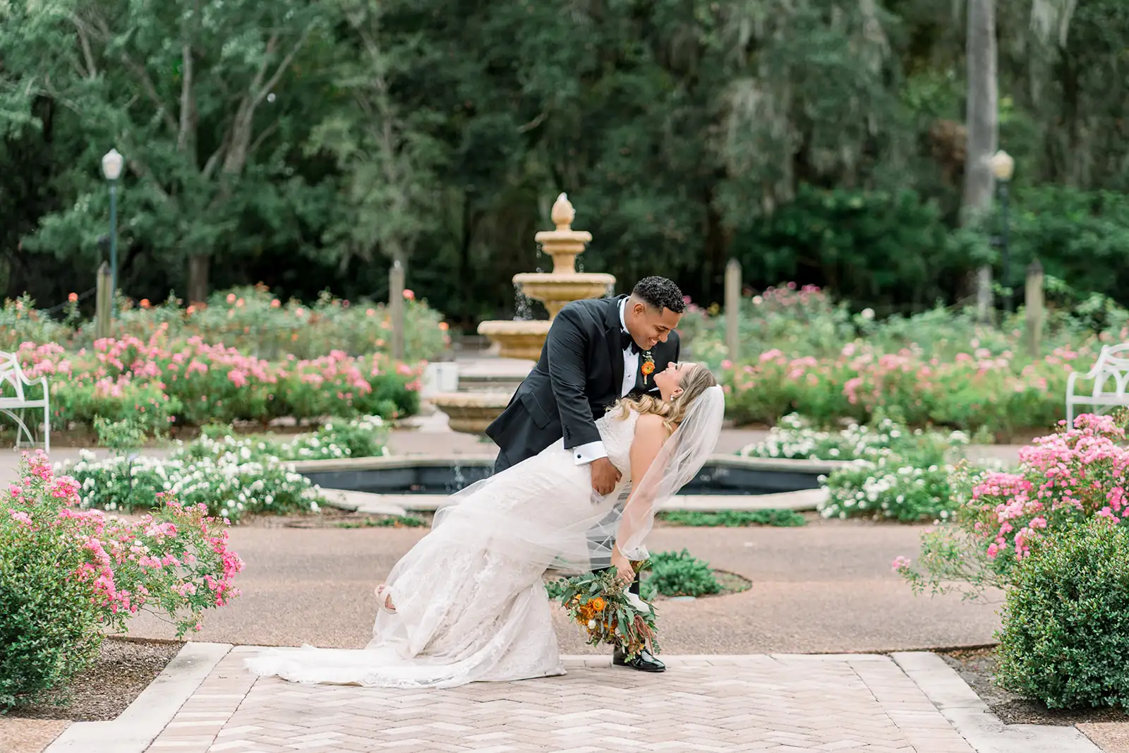 Groom dips bride in front of fountain at Florida garden wedding