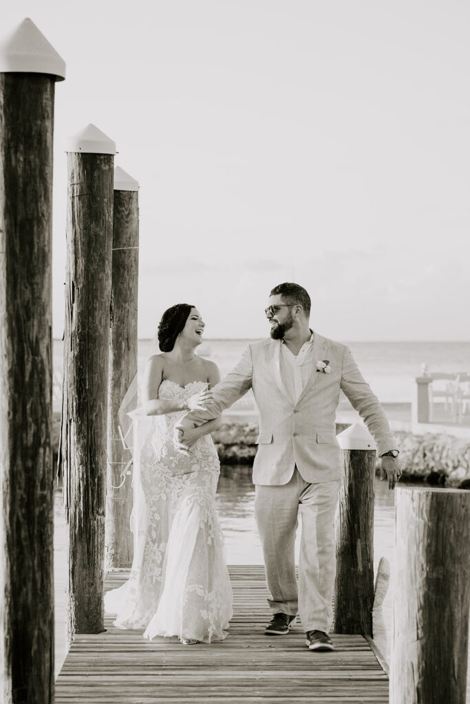 black and white photo fo bride and groom walking on dock