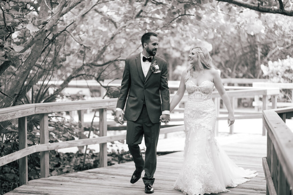 black and white photo fo bride and groom walking hand in hand