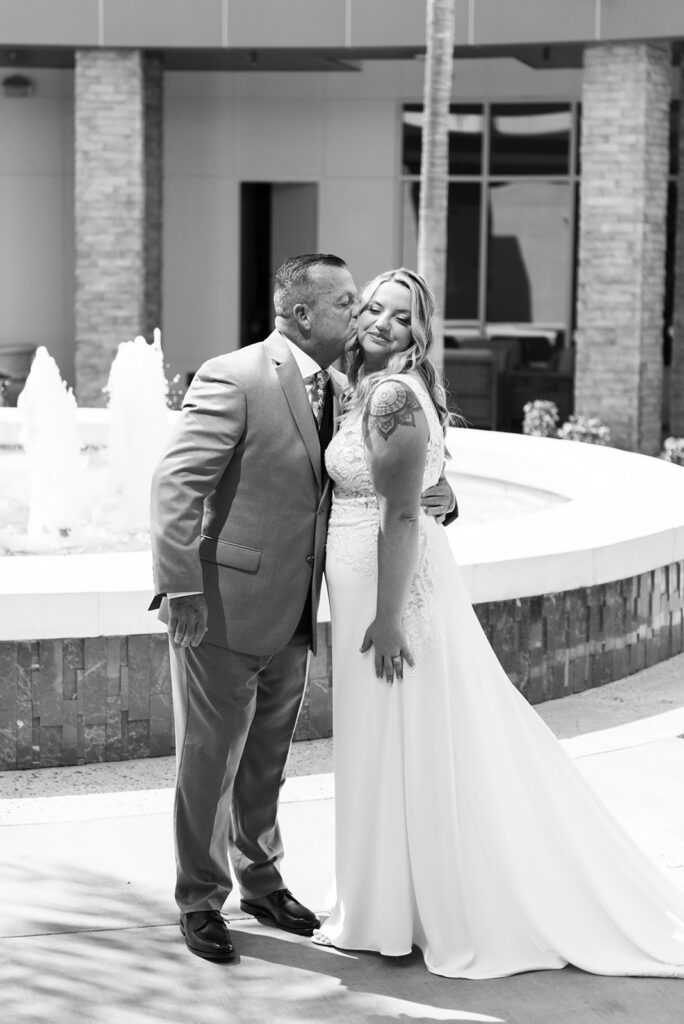 black and white photo of father kissing bride