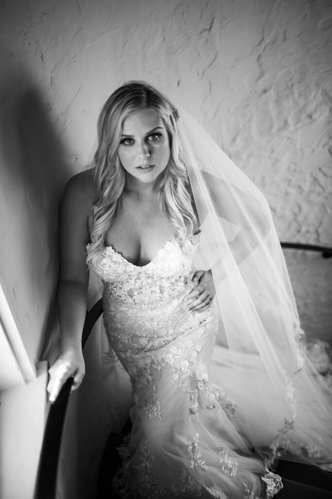 black and white photo of bride looking up staircase
