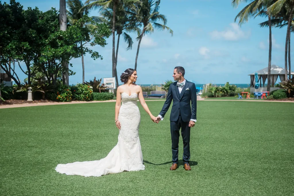 bride groom hold hands in green space by ocean in South FL