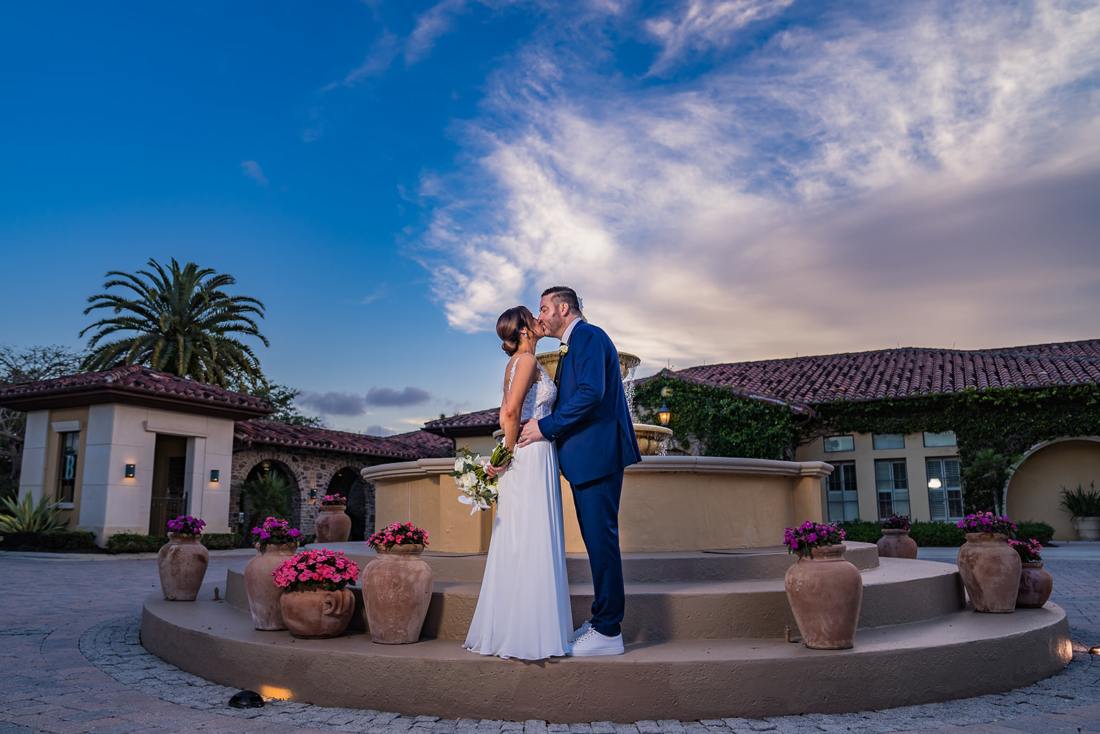 bride and groom kissing by fountain