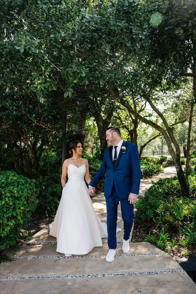 bride and groom walk down tree lined path