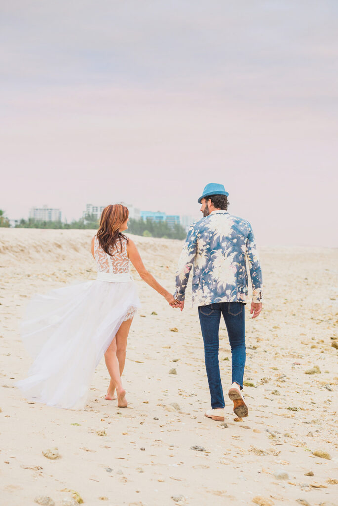 bride and groom walking on beach holding hands