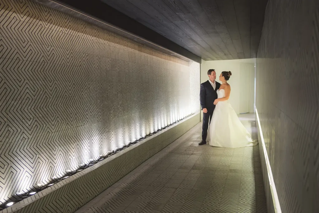 bride and groom in a long lighted hallway