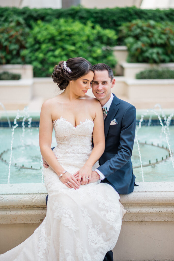 bride on groom's lap by fountain