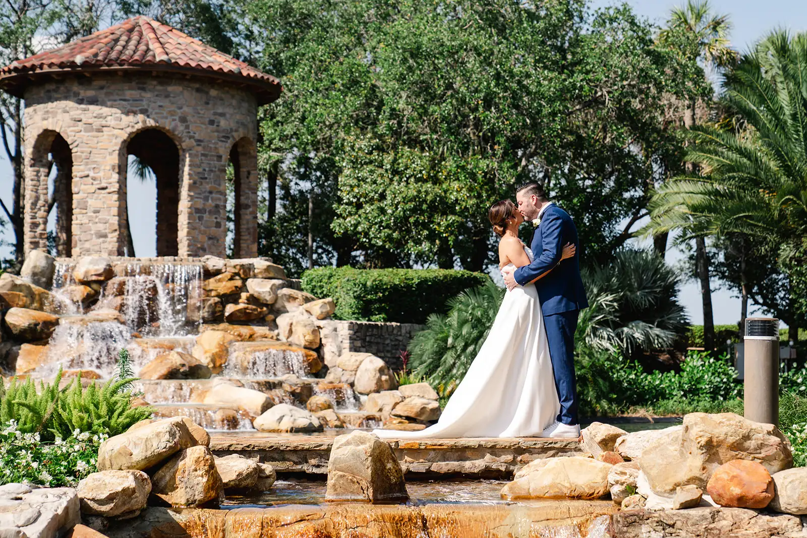 bride and groom standing amongst water feature