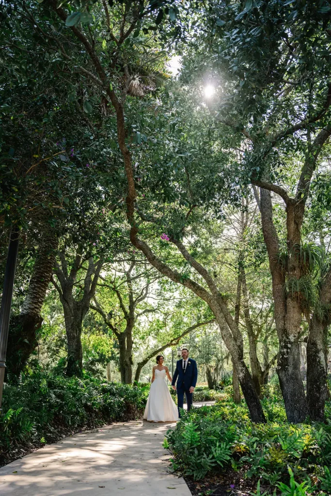 bride and groom walking down path covered by trees