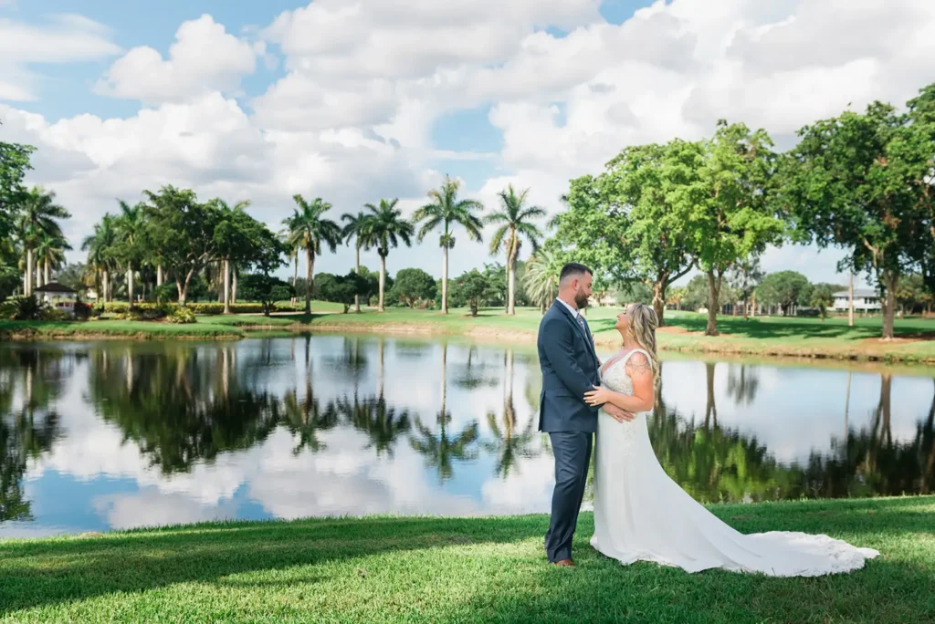 bride and groom standing by pond reflecting palm trees