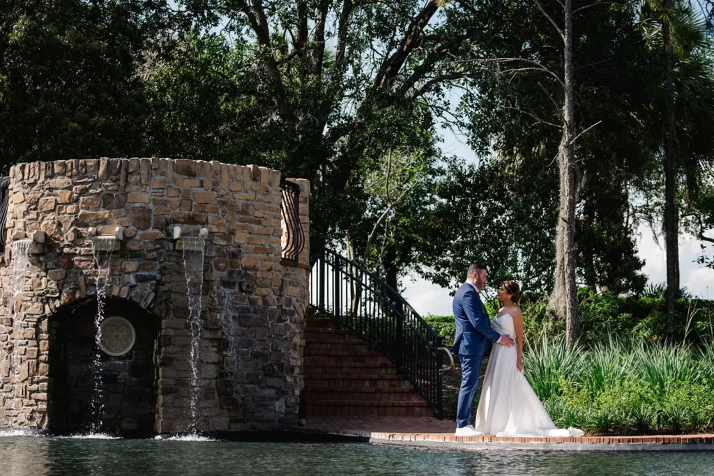 bride and groom beside pond and waterfall