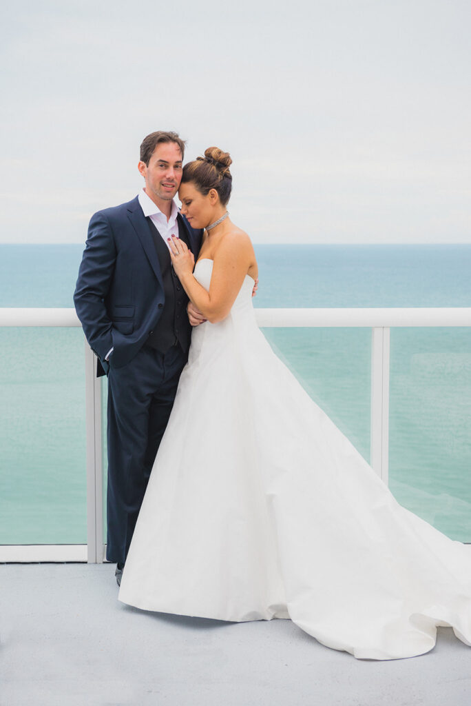 bride hugs groom by ocean
