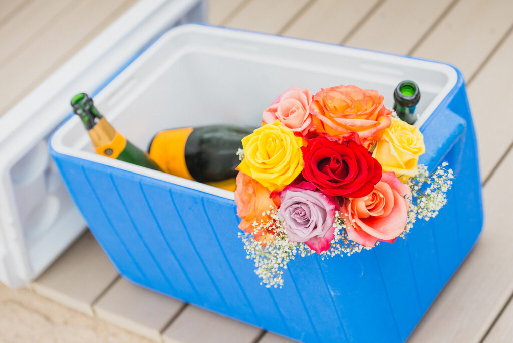 Blue cooler with champagne and colorful flowers inside