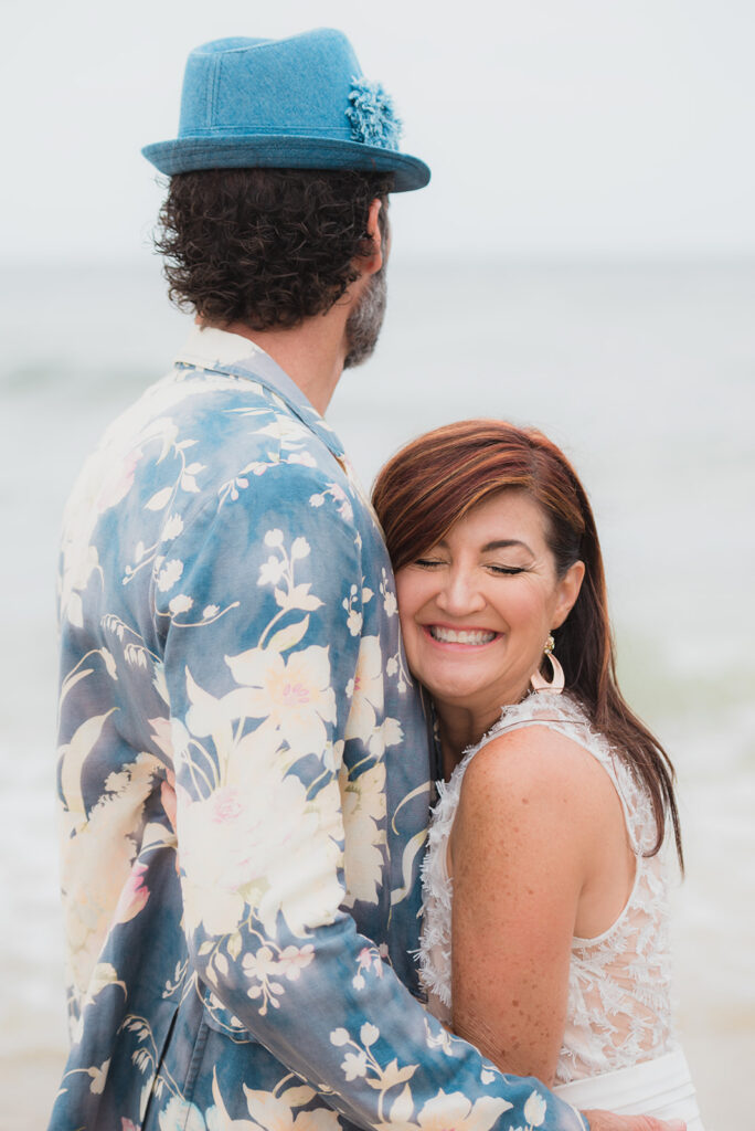 bride hugs groom who is wearing a blue hat and flowered jacket