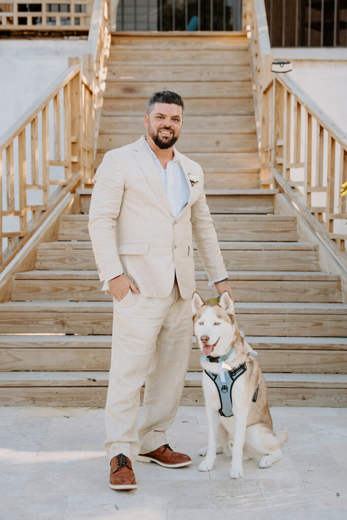 groom stand with dog by large staircase