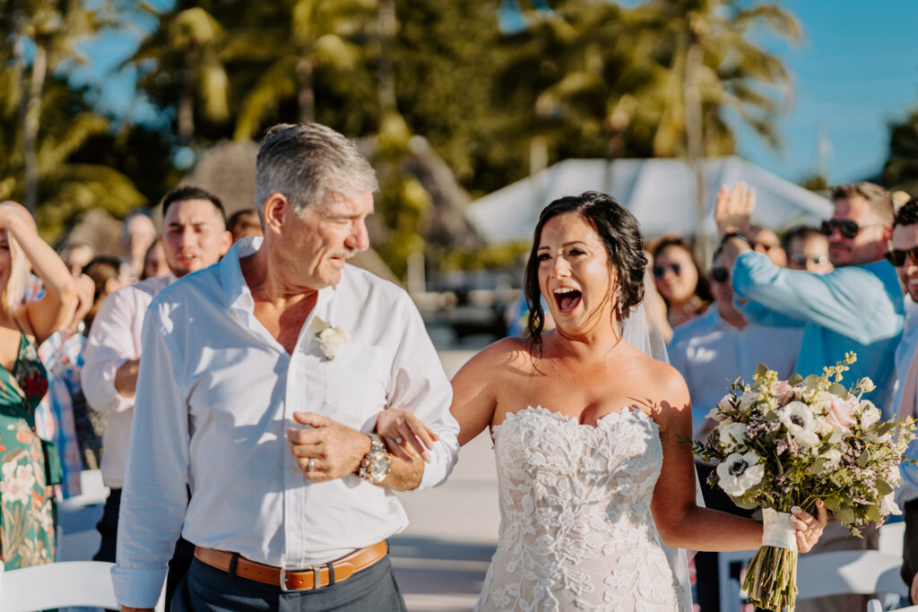 Bride smiling as father escorts down aisle