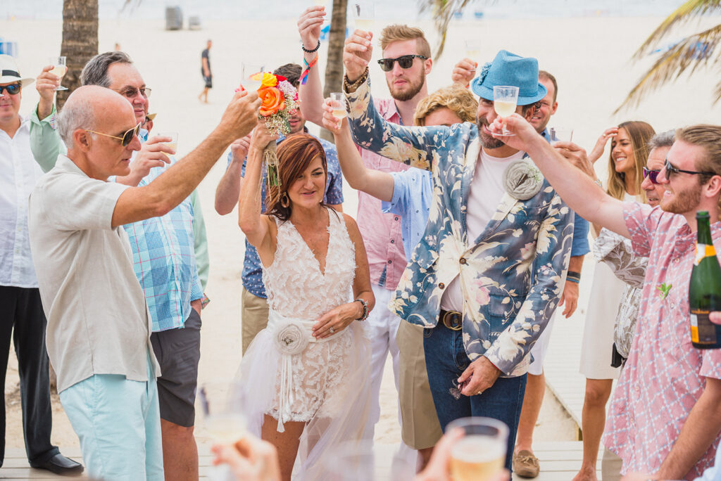beach wedding guests cheers to bride and groom