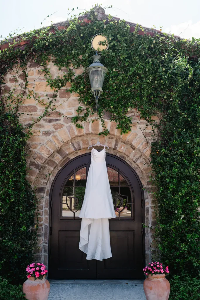 wedding dress hanging on brick walk covered in ivy