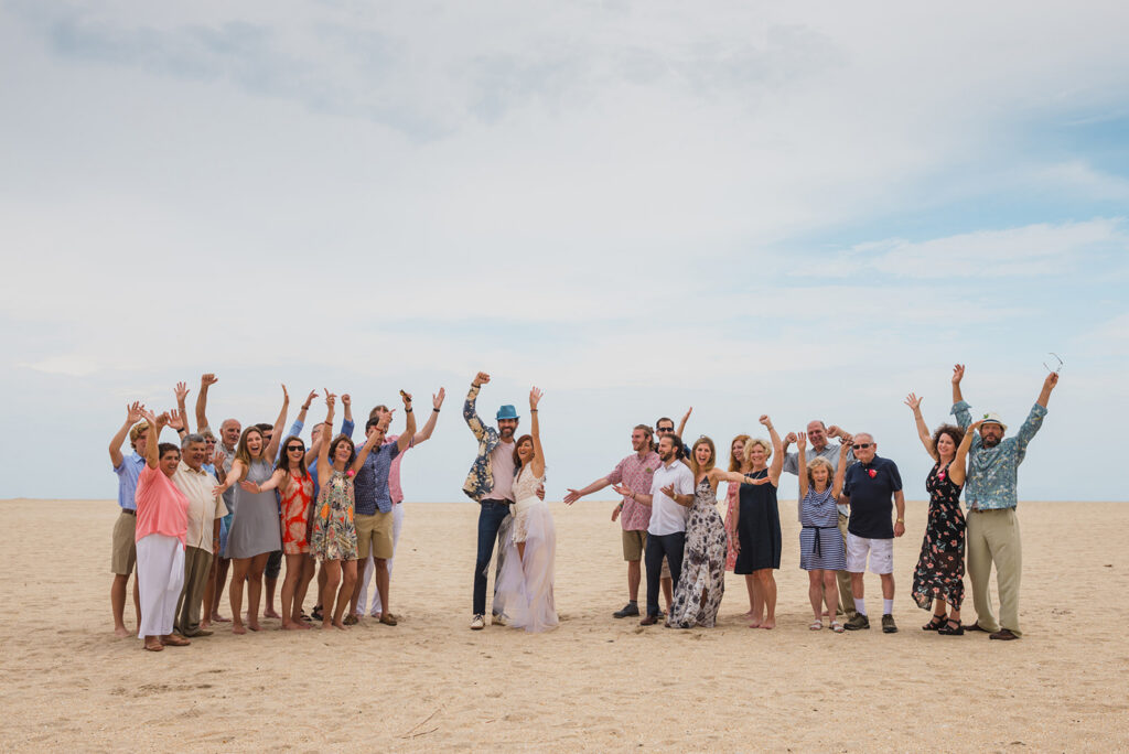 wedding guests celebrate on beach with bride and groom