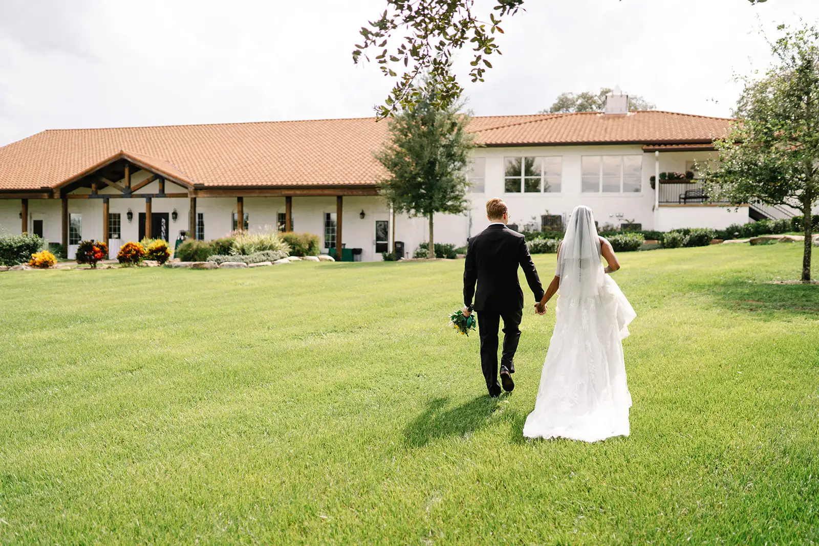 Bride and grooming walking away with Florida wedding venue in background