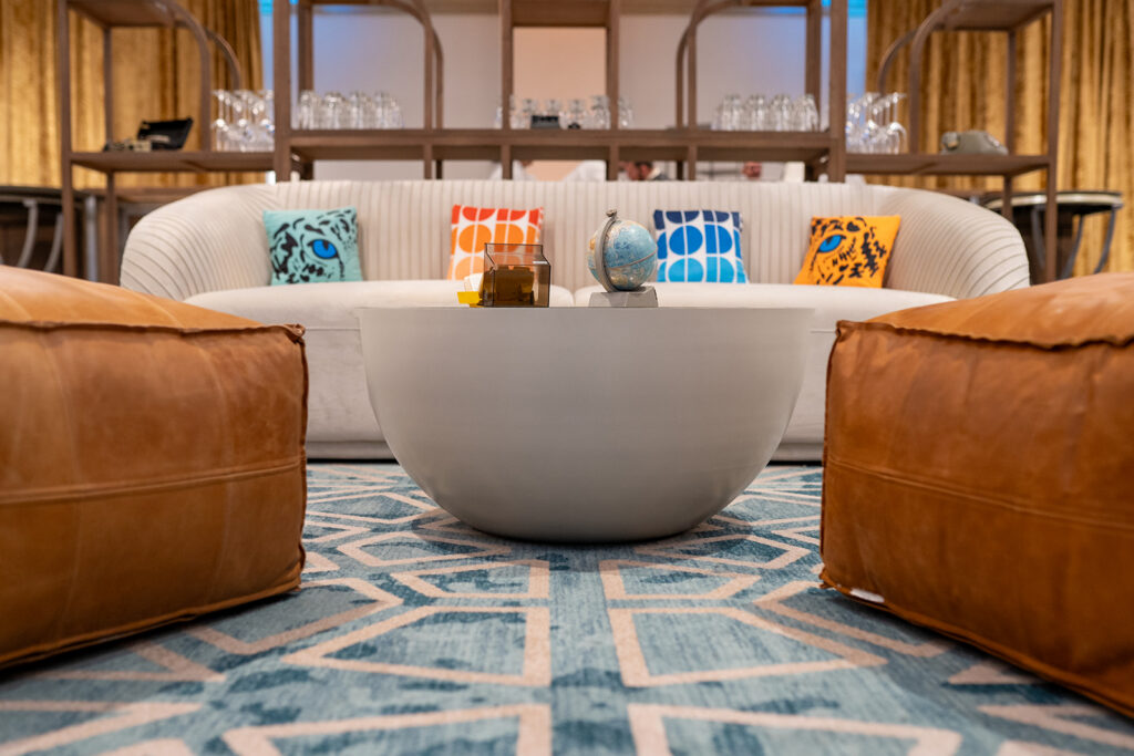 white couch and 2 orange chairs as themed sitting area at corporate event