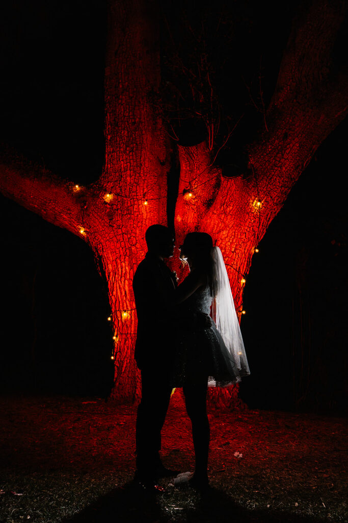 Red back lighting creates a unique backlit photo of bride and groom