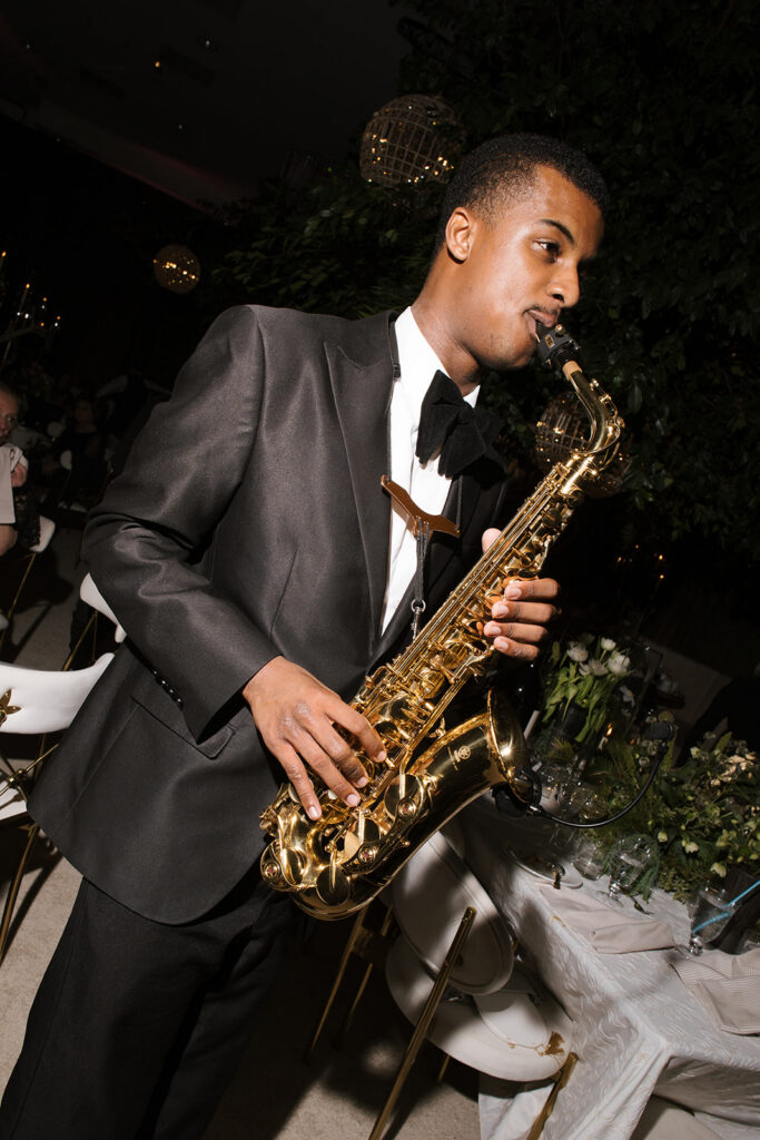 man wearing a black suit playing saxaphone at a wedding reception