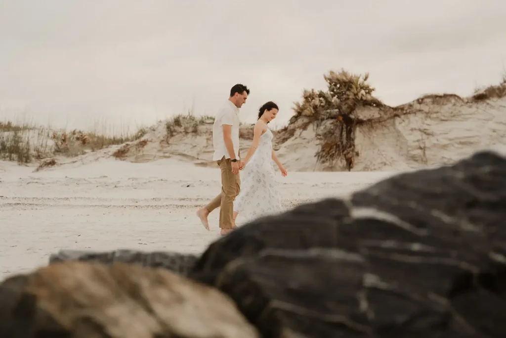 couple walking on beach holding handss