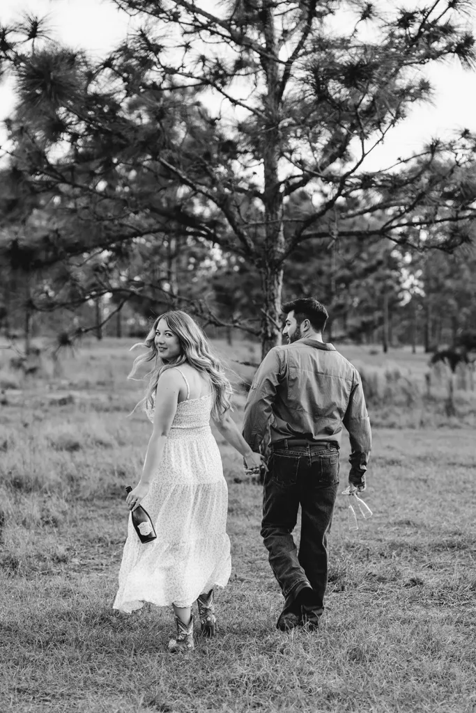 Man and woman walking in field with champagne