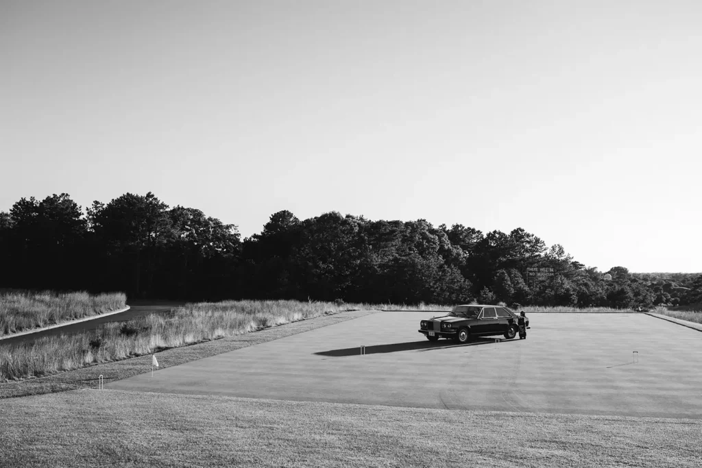 black and white photo of a vintage car in the middle of an empty golf course