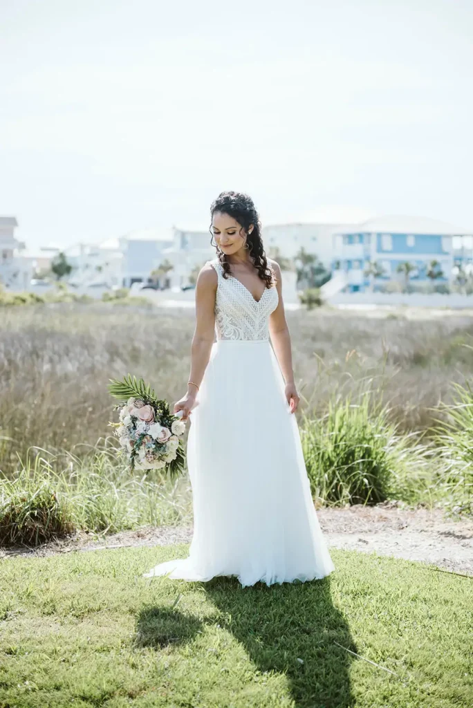 Bride stasnding on grass near beach wedding venue