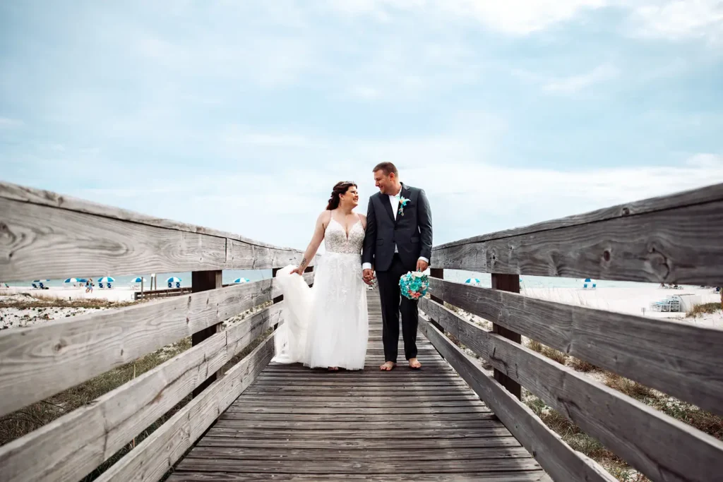 Bride and groom walking on boardwalk at beach