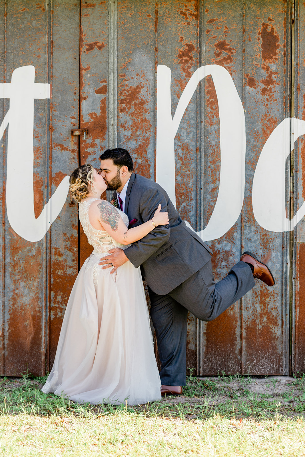 Bride and groom kissing in front of metal barn