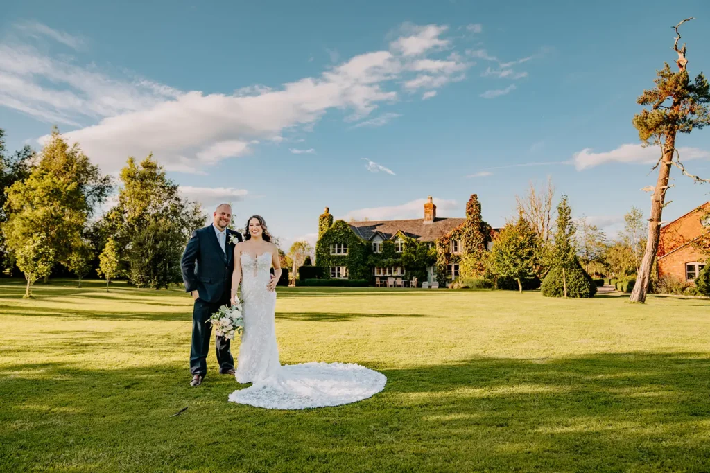 Bride and groom standing on lawn of private estate in UK
