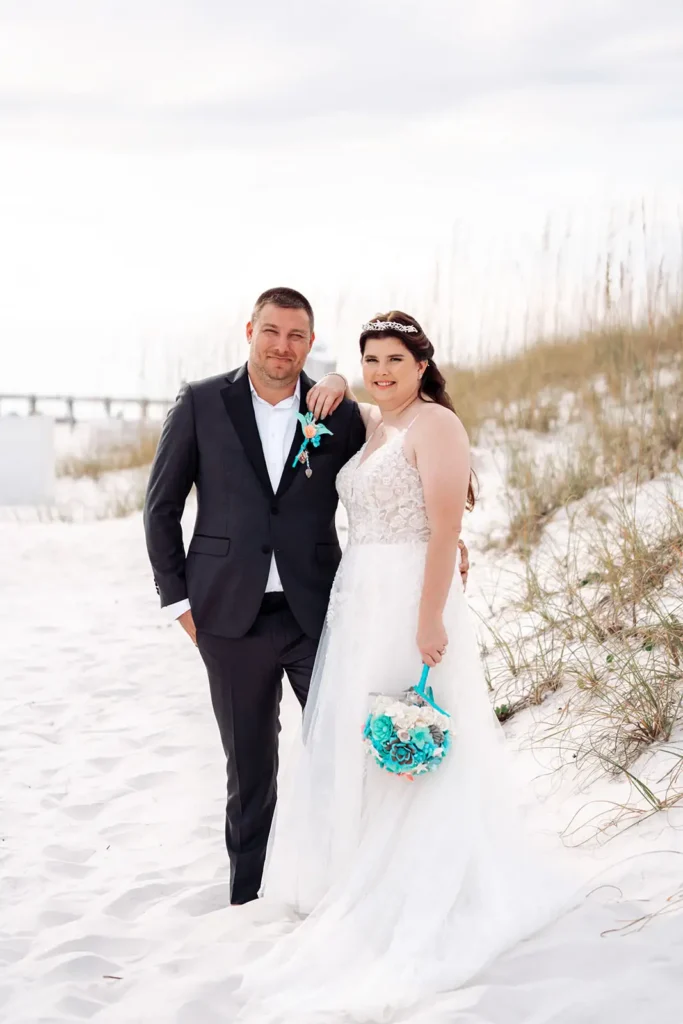 Bride and groom standing in sand on beach