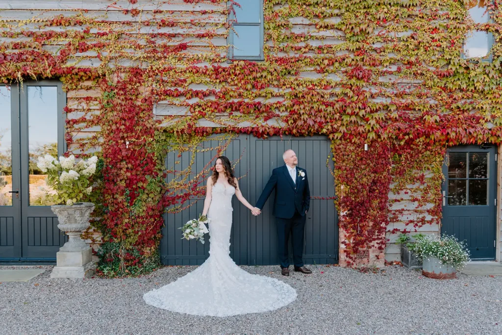 Bride and groom by wall covered in red vine