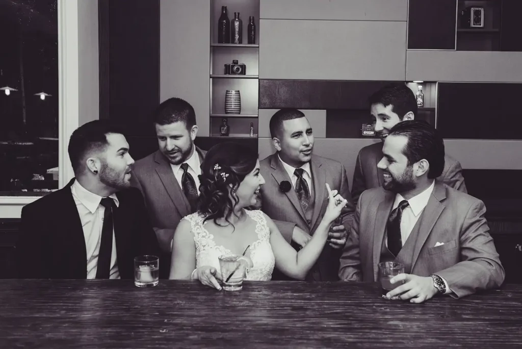 Black and white photo of bride and bridesmaids having cocktails at bar