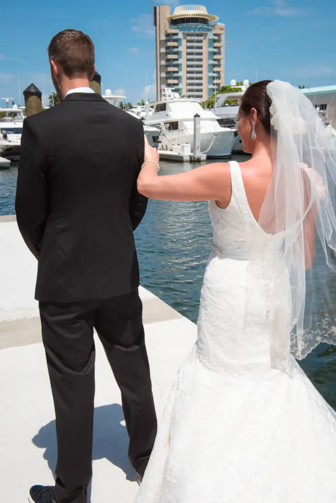 bride touches groom first look by water