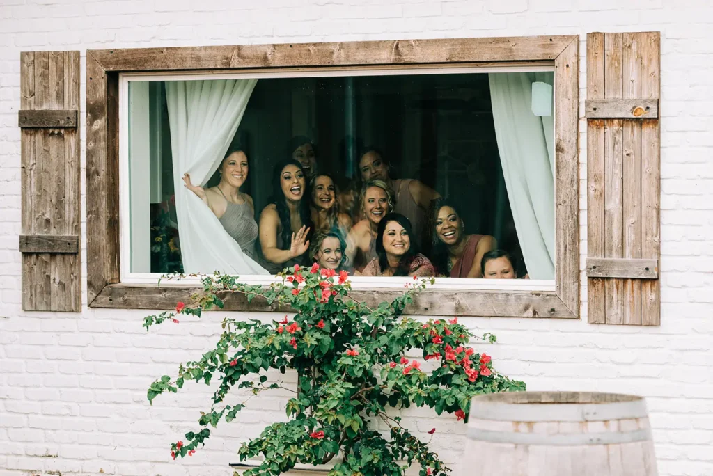 bridesmaids peak out window at bride
