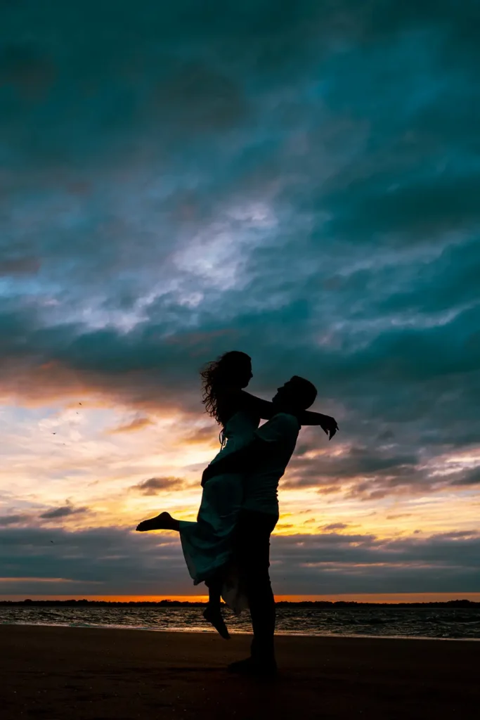 Couple embracing at beach sunset for engagement photo