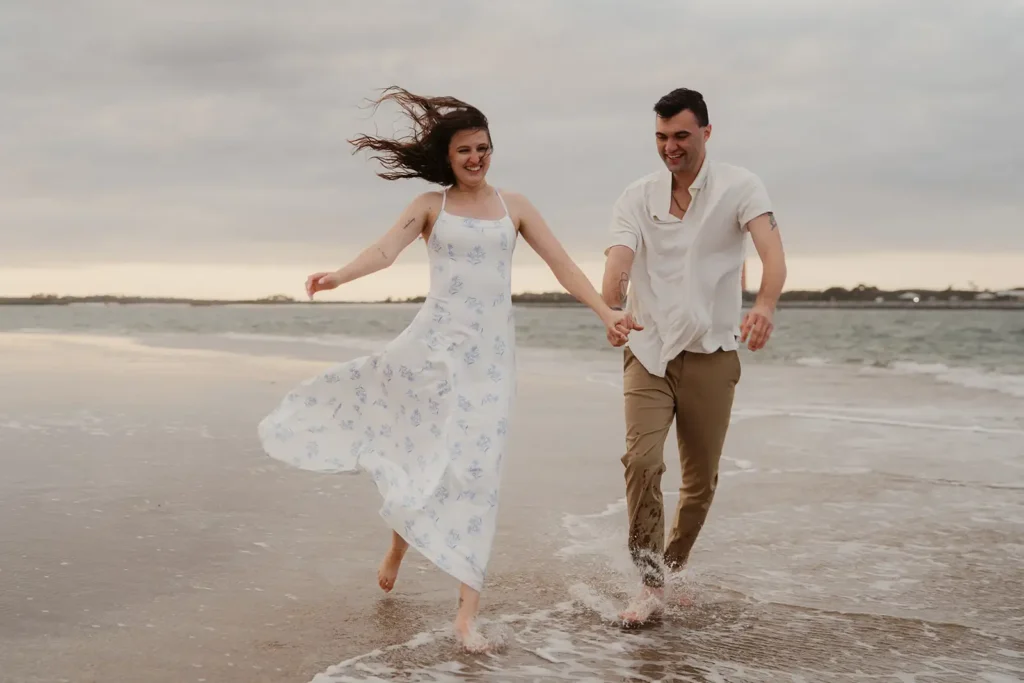 Engaged couple running in surf