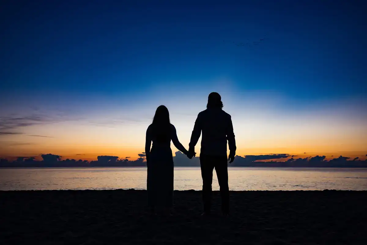 Engagement photo of couple silhouetted by sunset