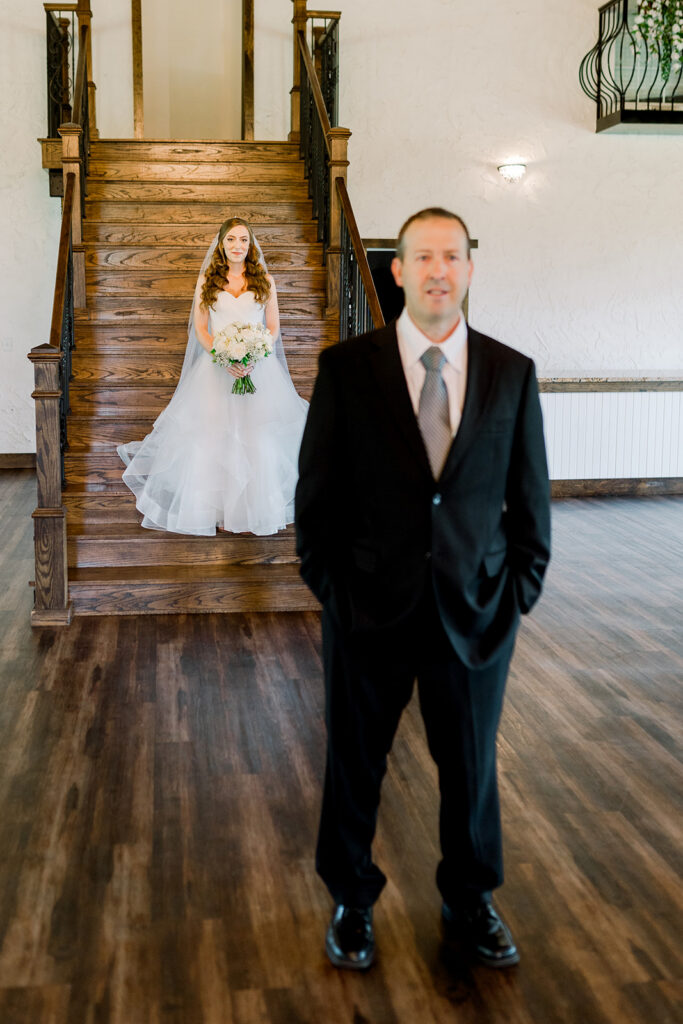 daughter descends stairs to father at wedding