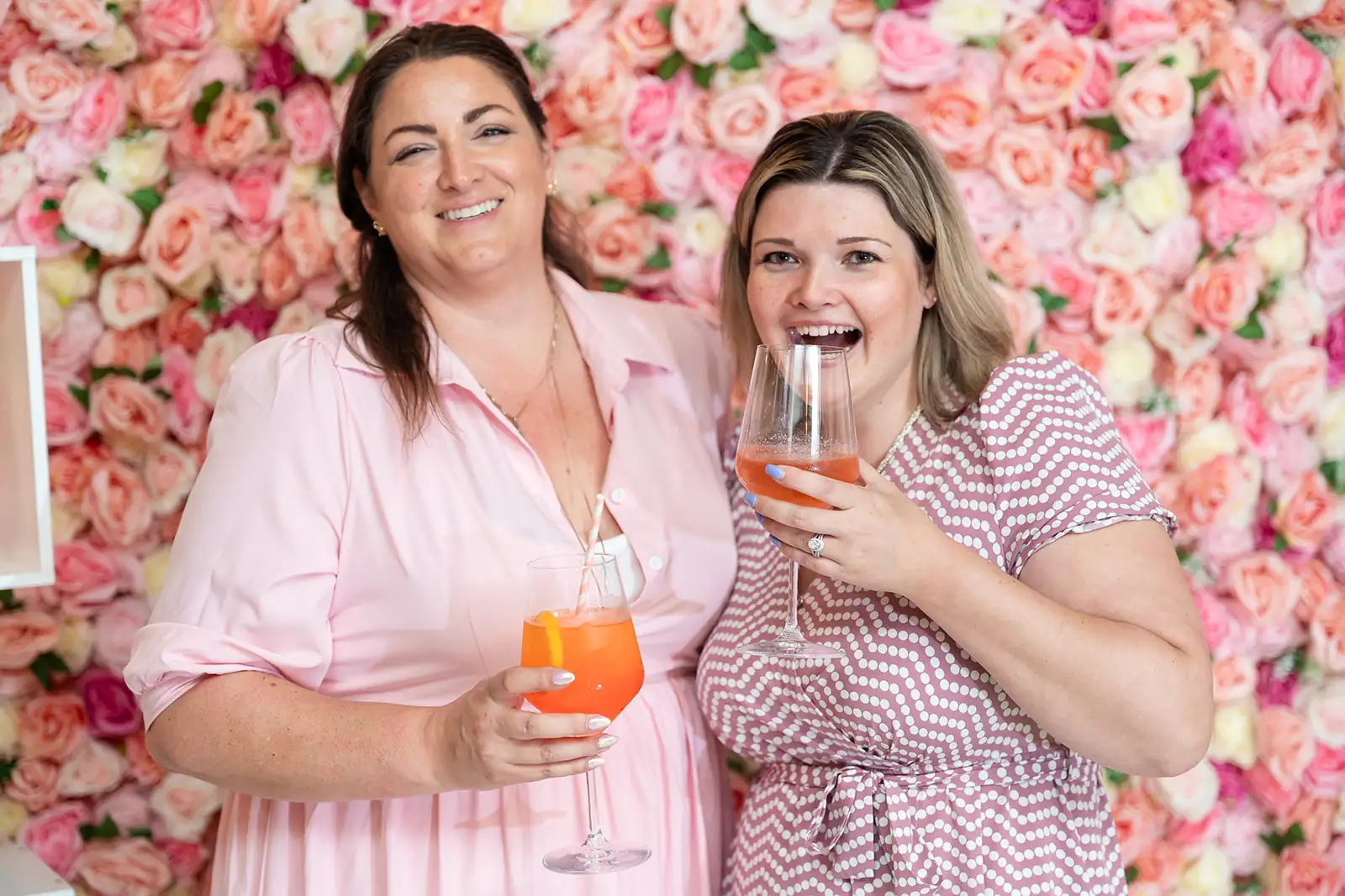 Two women wearing pink laughing and holding Rose spritzers