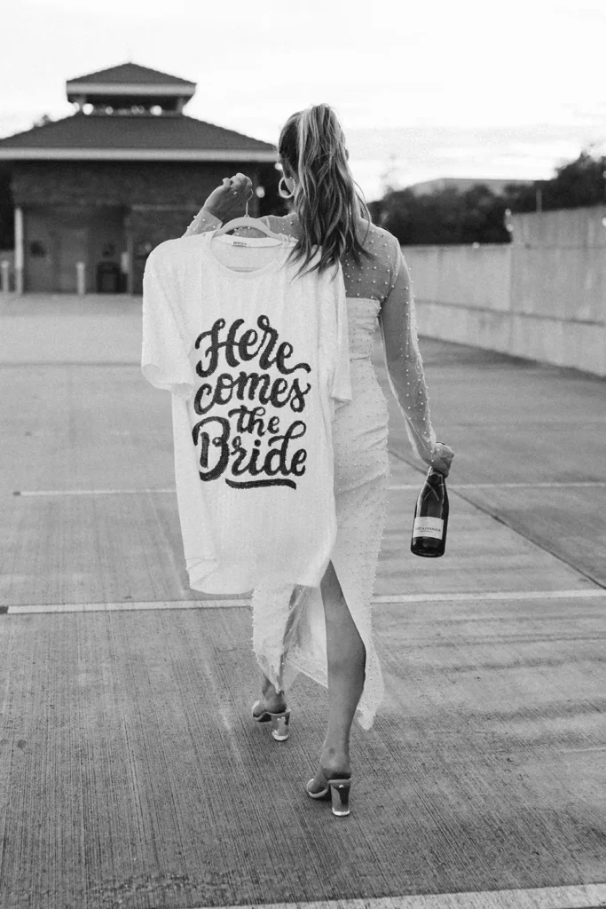 Bride with here comes the bride shirt and champagne