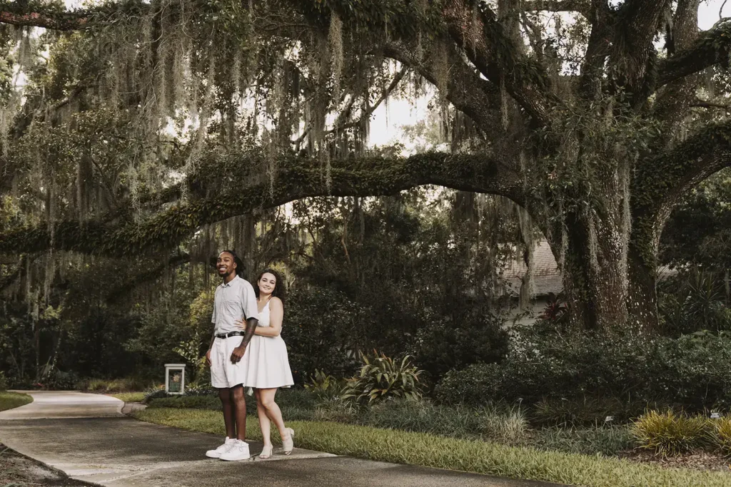 Couple under large oak tree for engagement photo by Cona Studios