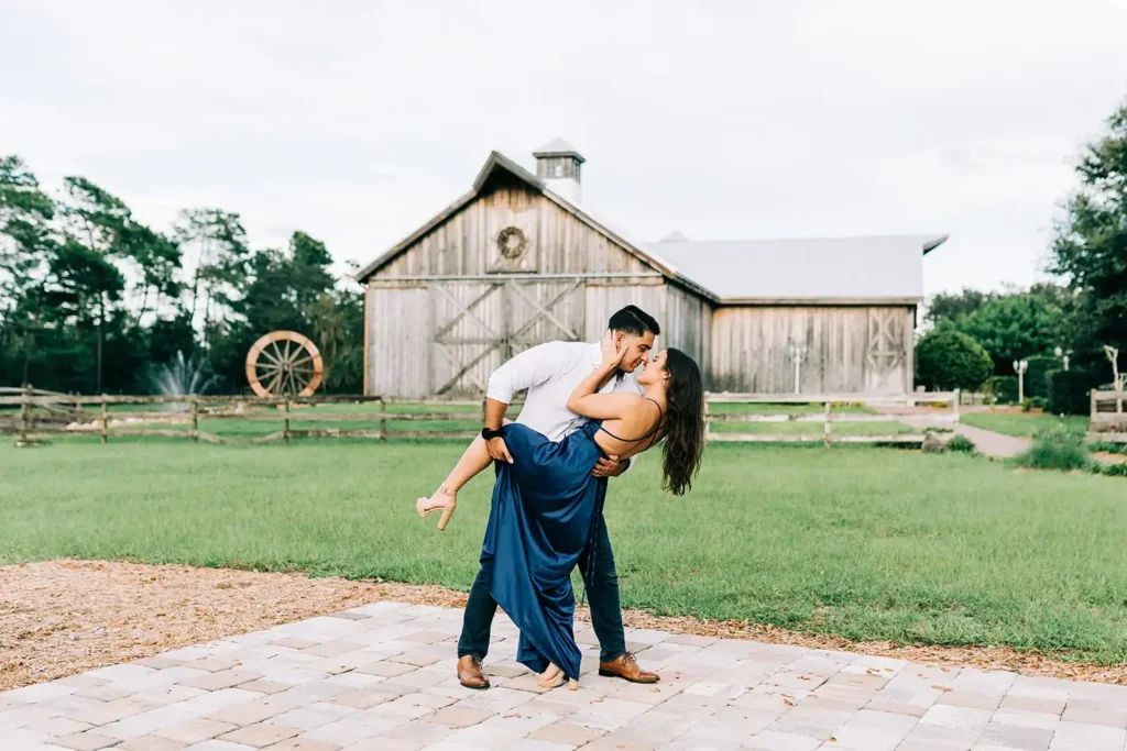 Man dips woman by barn for photo shoot