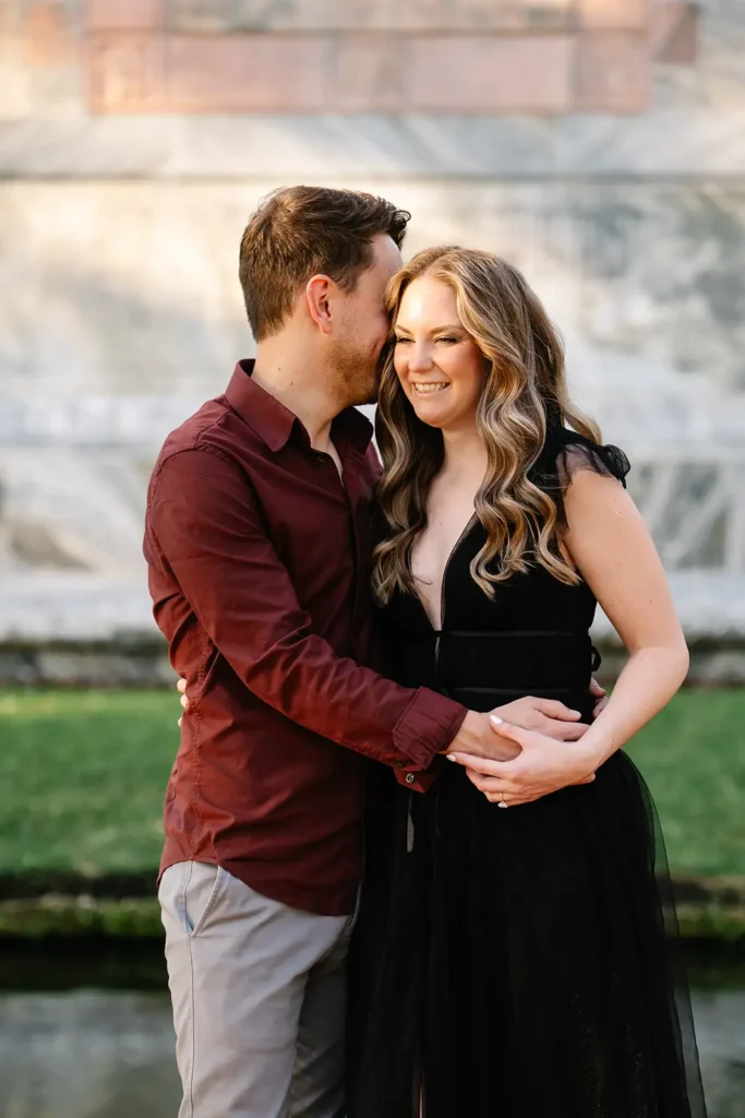 Man whispers in woman's ear at engagement photo shoot