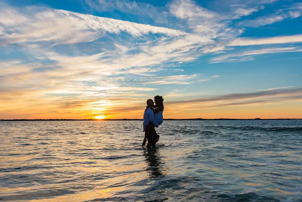 Portrait session of man and woman standing in the ocean at sunset