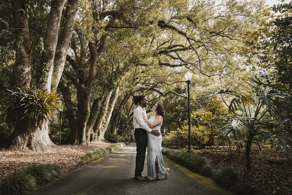 Couple under large trees on a walkway for engagement shoot